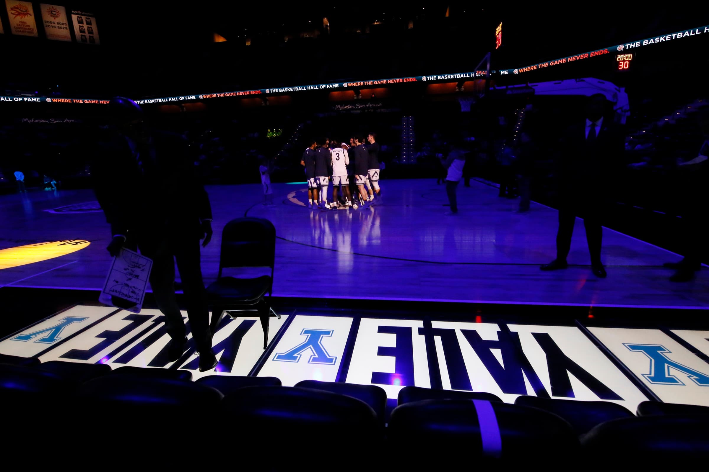 Courtside panels glowing with the Yale wordmark along the baseline as the team huddles on a darkened court
