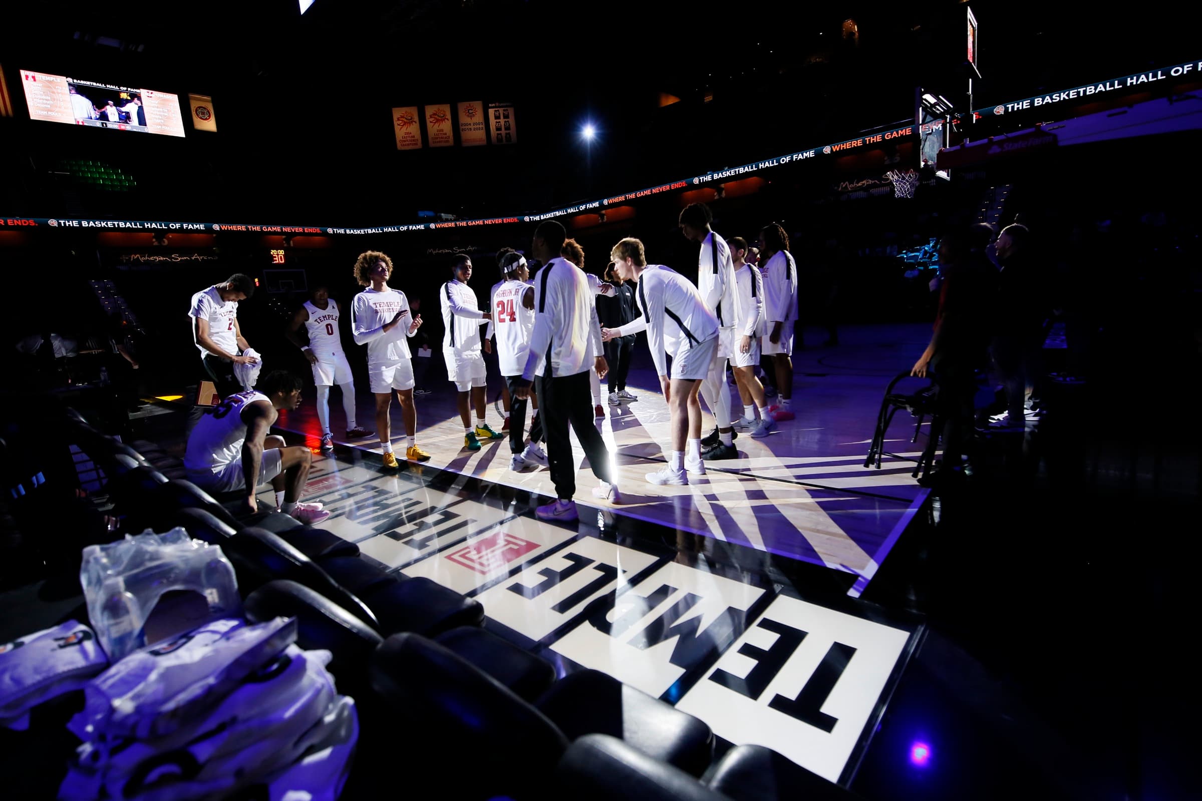 Players gathered under the arena spotlights beside the courtside seats