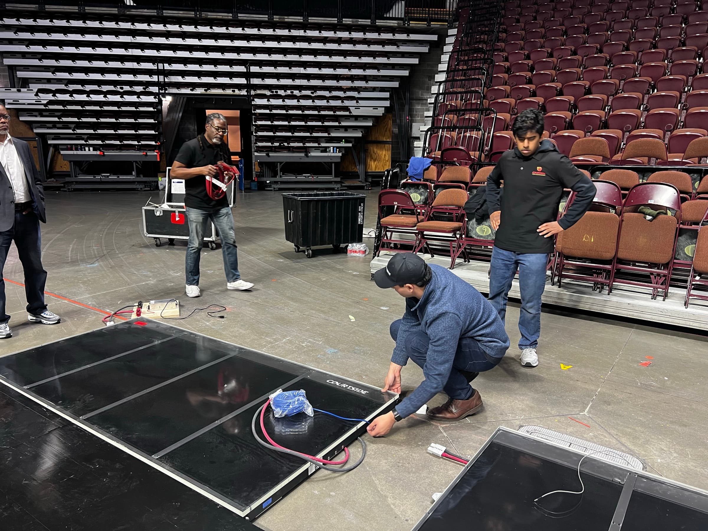 Courtside crew connecting display panels laid out on an arena floor during installation